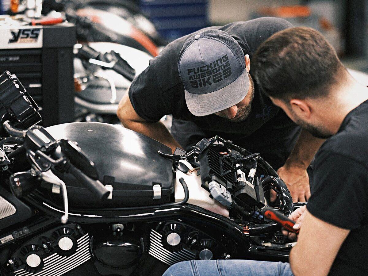 Zwei Mitarbeiter arbeiten gemeinsam an einem Motorrad in der Werkstatt