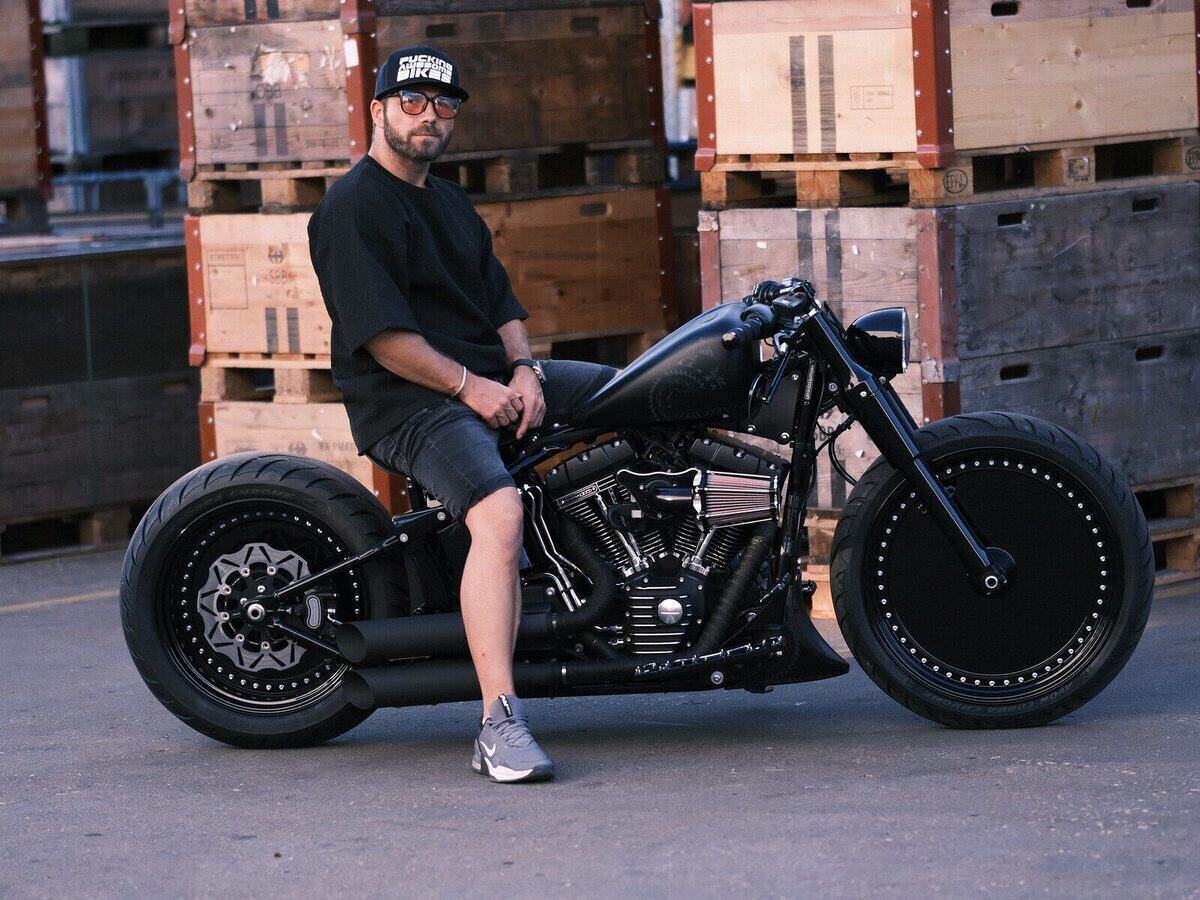Mitarbeiter von SLC Motorbikes auf einem Bobber vor Holzkisten