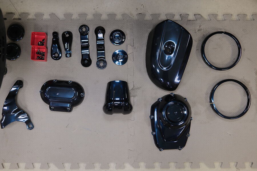 Kompletter Teilesatz einer Harley in Chamäleon-Effektfarbe, von oben aufgereiht: Deckel, Halter, Abdeckungen und Ringe