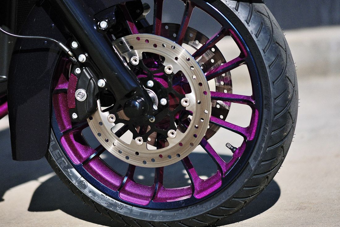 Vorderrad des Trikes mit Felge in Magenta und Bremsscheibe